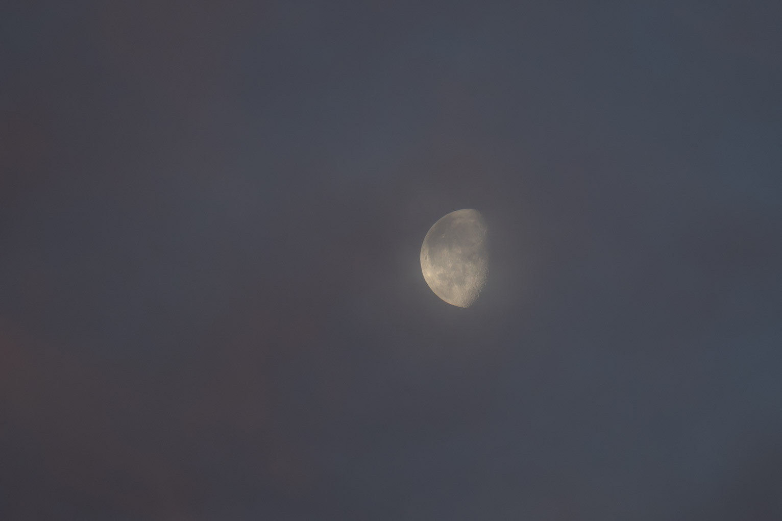 The gibbous moon near red lit clouds